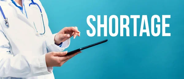 Shortage theme with a doctor using a tablet — Stock Photo, Image