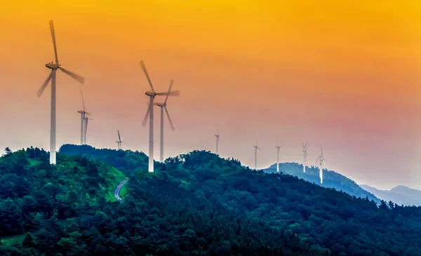 Gün batımında dağın tepesinde rüzgar türbinleri — Stok fotoğraf