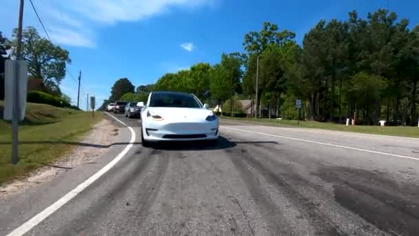 Um novo Tesla Model 3 dirigindo pela estrada — Vídeo de Stock