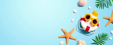 Güneş gözlüğü takan güneş kremi şişesi, deniz yıldızı ve deniz kabuğu.