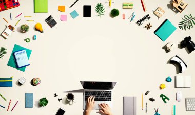 Ofis malzemesi olan bir dizüstü bilgisayar kullanan kişi.