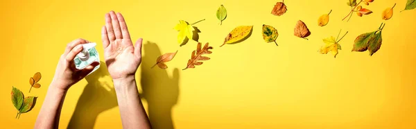 Aplicación de gel desinfectante con hojas de otoño —  Fotos de Stock