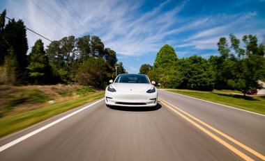 Yeni bir Tesla Model 3 tamamen elektrikli araba yolda ilerliyor.