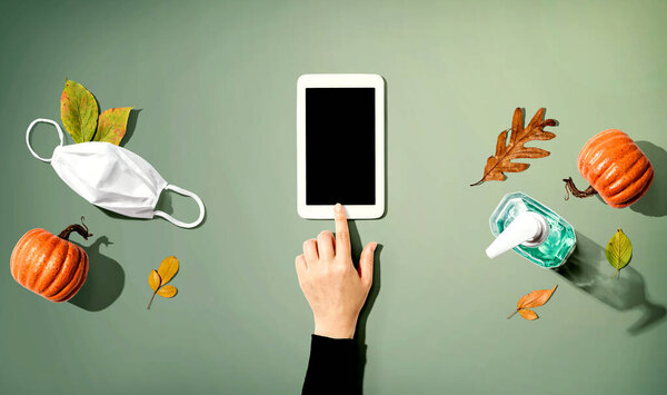 Tablet with a mask and a sanitizer bottle in Autumn