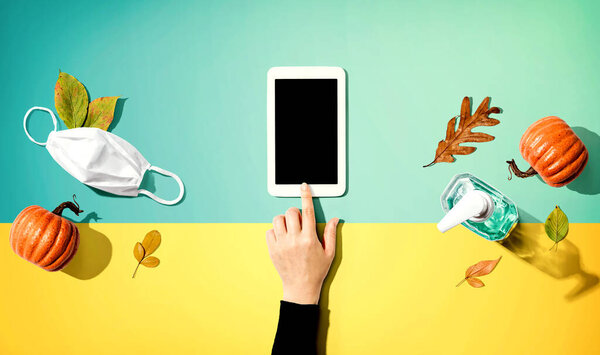 Tablet with a mask and a sanitizer bottle in Autumn