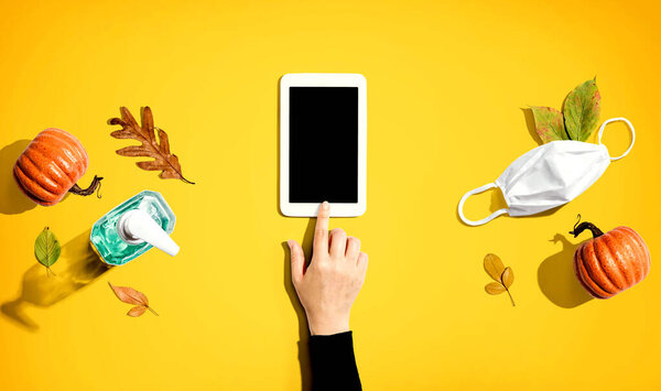Tablet with a mask and a sanitizer bottle in Autumn