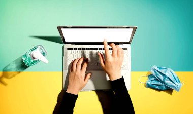 El dezenfektanı ve maskeli dizüstü bilgisayar.