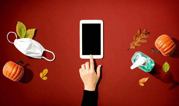 Tablet with a mask and a sanitizer bottle in Autumn