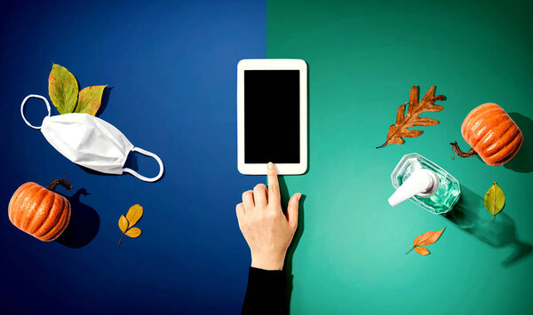 Tablet with a mask and a sanitizer bottle in Autumn
