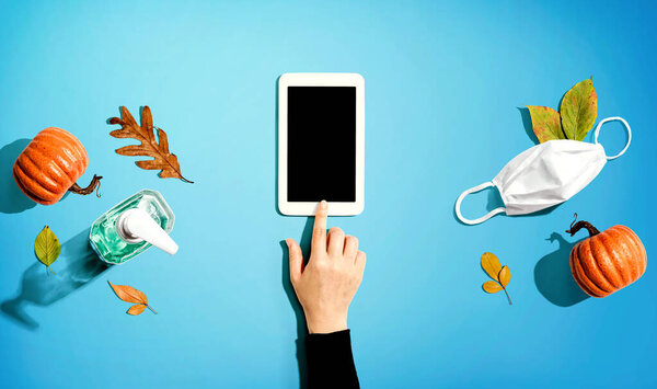Tablet with a mask and a sanitizer bottle in Autumn