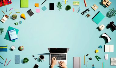 Ofis malzemesi olan bir dizüstü bilgisayar kullanan kişi.