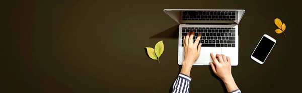 Folhas de outono com pessoa usando um computador portátil — Fotografia de Stock