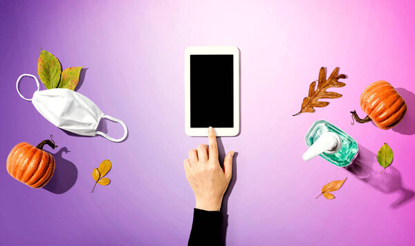 Tablet with a mask and a sanitizer bottle in Autumn