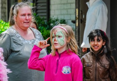 A girl with a facial painting of a butterfly in her face.