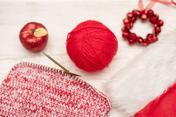 red knitting needles, yarn and toy apple