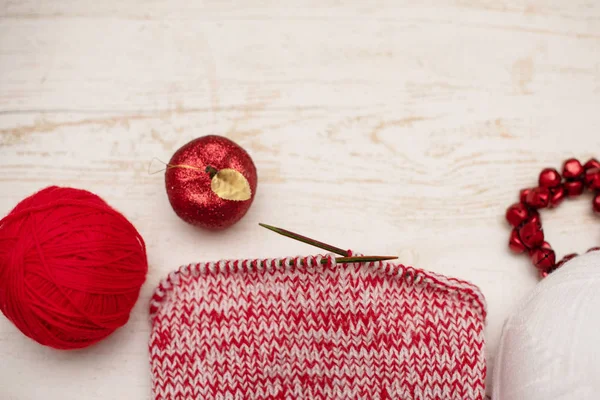 red knitting needles, yarn and toy apple