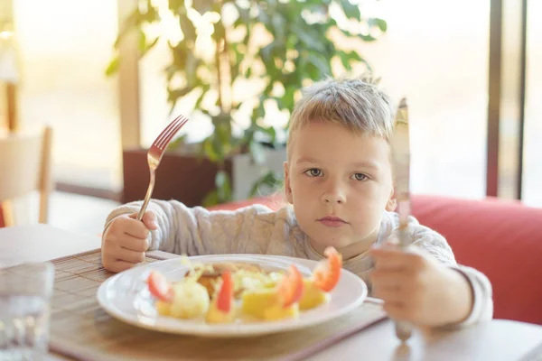adorable little boy eating meat and vegetables