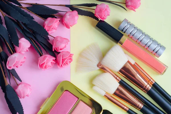 premium makeup brushes, blush and lipstick on a colored pink and yellow background, creative cosmetics flat lay