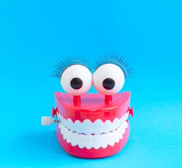 toy with smiling teeth and eyes on blue background as a concept of dentistry and healthy oral cavity and smile