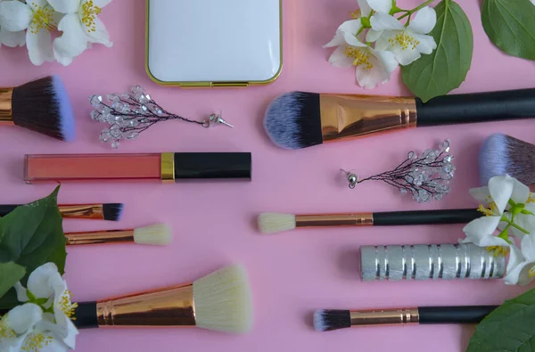 premium makeup brushes, eyeshadow palette and blush on a colored pink background, creative cosmetics flat lay