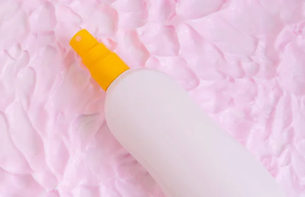 pink cream texture and a bottle of sunscreen