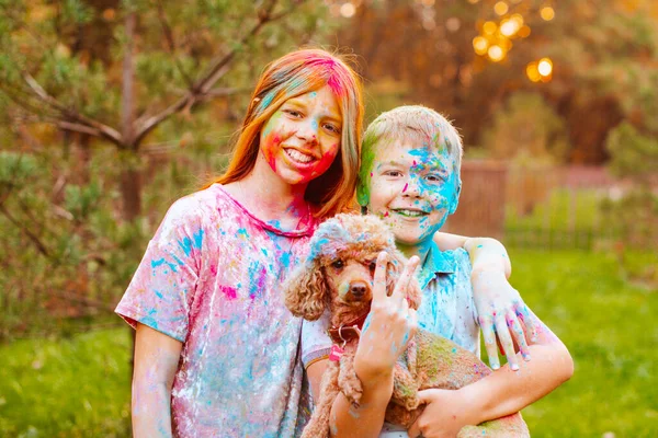 happy boy and girl with a dog painted with Holi festival colours in autumn park