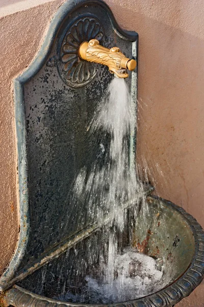 water running in a public drinking fountain with brass tap