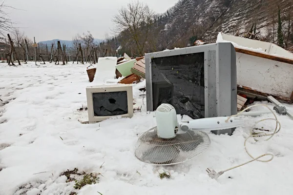 electronic waste and electrical appliance abandoned in the snow -  illegal waste dump in the countryside