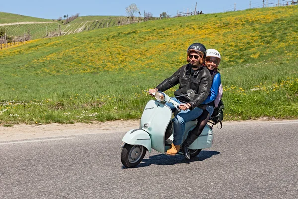 an happy couple riding a vintage scooter Vespa in the italian countryside during the scooters rally 