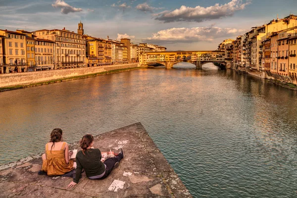 tourism in cities of art: two young girls draws a sketch of Ponte Vecchio, the famous old bridge over the Arno river, on April 17, 2013 in Florence, Italy