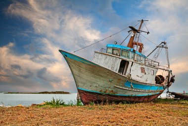 Po Delta Park, Porto Tolle, Veneto, İtalya: dramatik gökyüzü altında deniz kıyısında eski terk edilmiş balıkçı teknesi