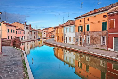 Comacchio, Ferrara, Emilia Romagna, Italy: view of the colored houses with mirror on the water of the canal in the old town known as the Little Venice clipart