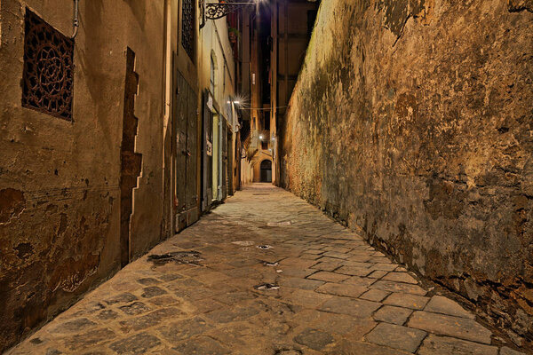 Florence, Tuscany, Italy: dark narrow alley in the old town at night lit by old street lamp