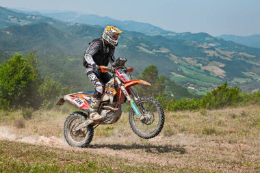 biker riding enduro motorcycles KTM 450 EXC in the green hills during the Italian championship Motorally Terre di Romagna, on July 5, 2015 in Predappio, FC, Italy clipart