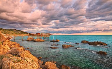 Rocca San Giovanni, Chieti, Abruzzo, İtalya: manzara ile dramatik bir bulutlu gökyüzü altında tipik Akdeniz balıkçılık kulübe trabocco şafak Adriyatik Denizi kıyılarının