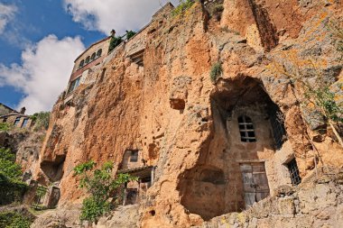 Civita di Bagnoregio, Viterbo, Lazio, Italy: the rock face of the tuff hill where it was built the medieval village with caves and rock-cut cellars clipart