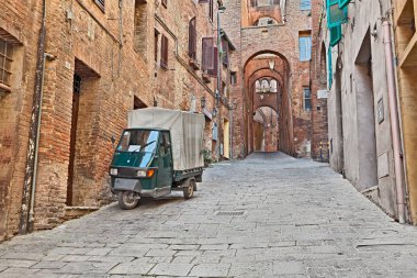 Siena, Toskana, İtalya: pitoresk İtalyan sokakta eski evler, gözlerden ve üç tekerlekli araç maymun Piaggio tarihi kent. 22 Mart 2016 yılında çekilmiş fotoğrafı
