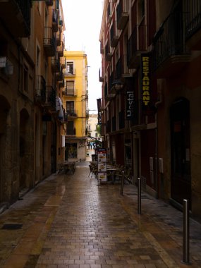 İspanya Tatil serisi. Tarragona dar sokakta. Sarı tuğla duvar ve taş döşeli kaldırım konuda seyahat, yaz, tatil.