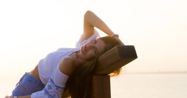 İspanya Tatil serisi. Seyahat, yaz, tatil, gençlik, Güzellik, günbatımı konuda bir plajda beyaz bluz ve kot şortlu genç kız.