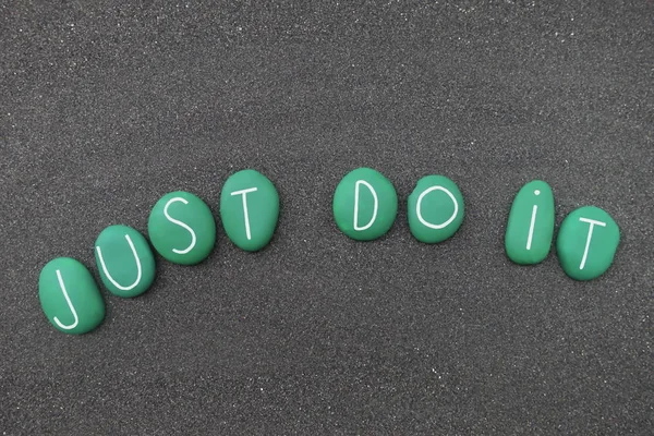 Just do it, motivational phrase composed over black volcanic sand with green colored stone letters