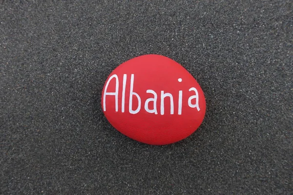 Albania, country name carved on a red painted stone over black volcanic sand
