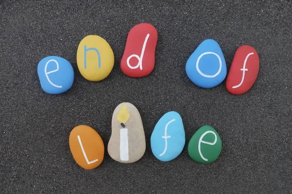 End of life phrase with a composition of colored stones over black volcanic sand