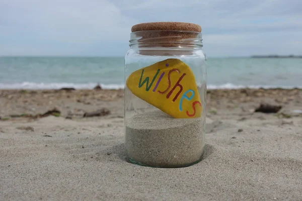 Wunschwort Auf Einem Farbigen Stein Einem Glas Mit Sand Geschnitzt — Stockfoto