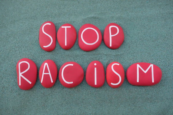 Стоп расизм слоган, составленный из красного цвета каменные буквы на зеленый песок
