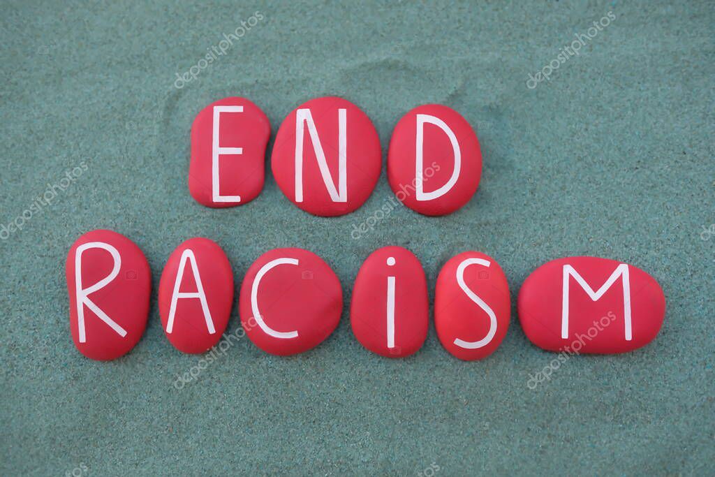 End Racism, social issue text composed with red colored stone letters over green sand