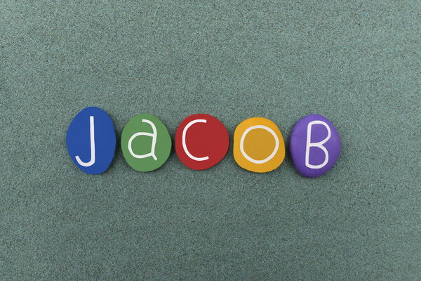 Иаков, мужское имя составлено из разноцветных каменных букв на зеленом песке
