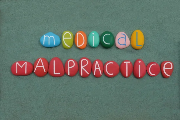 Medical malpractice, multicolored stone letters text over green sand
