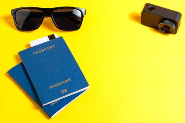 Eğlence ve Turizm kavramı. biyometrik pasaport, güneş gözlüğü ve malzemeleri parlak sarı bir arka plan üzerinde seyahat edenler için