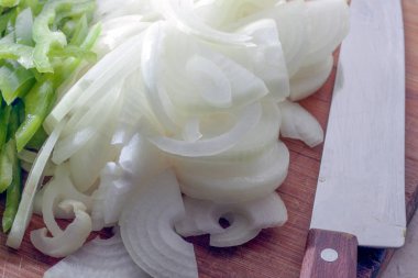 Yeşil biber, beyaz soğan ve bir kesme tahtası üzerinde bir bıçak. Taze ve son zamanlarda dilimlenmiş sebzedir. Sağlıklı beslenme ve yaşam tarzı kavramı.