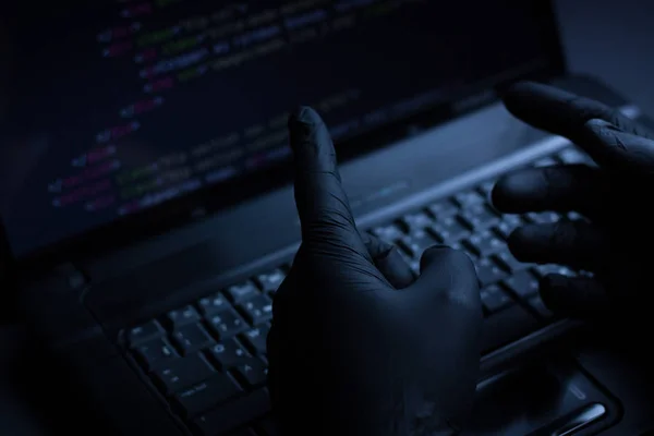 Internet hacker hırsız kavramı. Hacker dizüstü bilgisayar ekipmanı saldırmak için kullanma. Karanlık ve korkunç aydınlatma. Bir sürü bilgisayar ekranında sembolleri. Seçici odak.